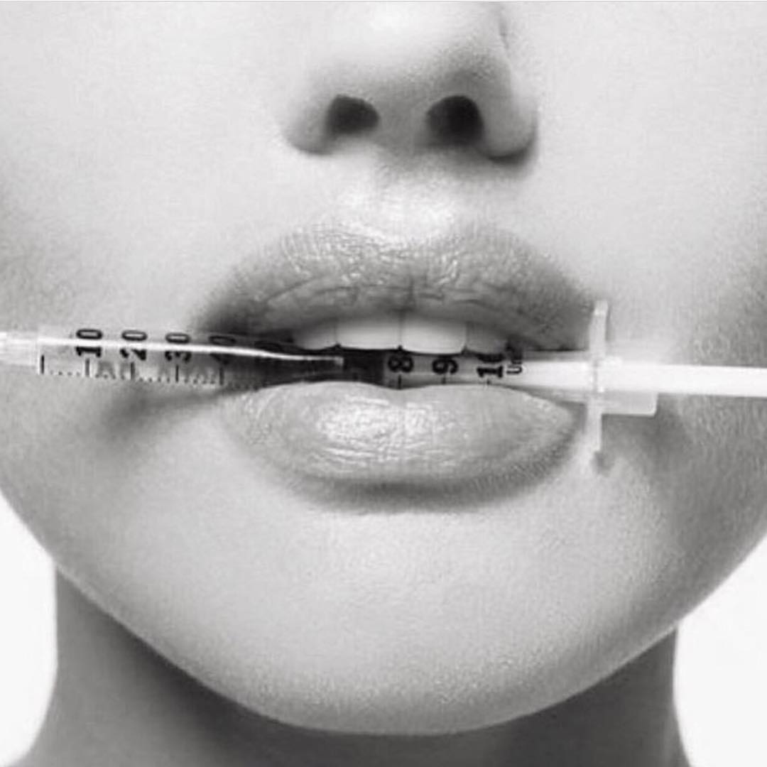 A woman holding a botox syringe with her mouth A woman holding a botox syringe of Peace.Love.Med. with her mouth