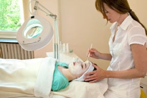 alternative practitioner applying a chemical peel to a female patient