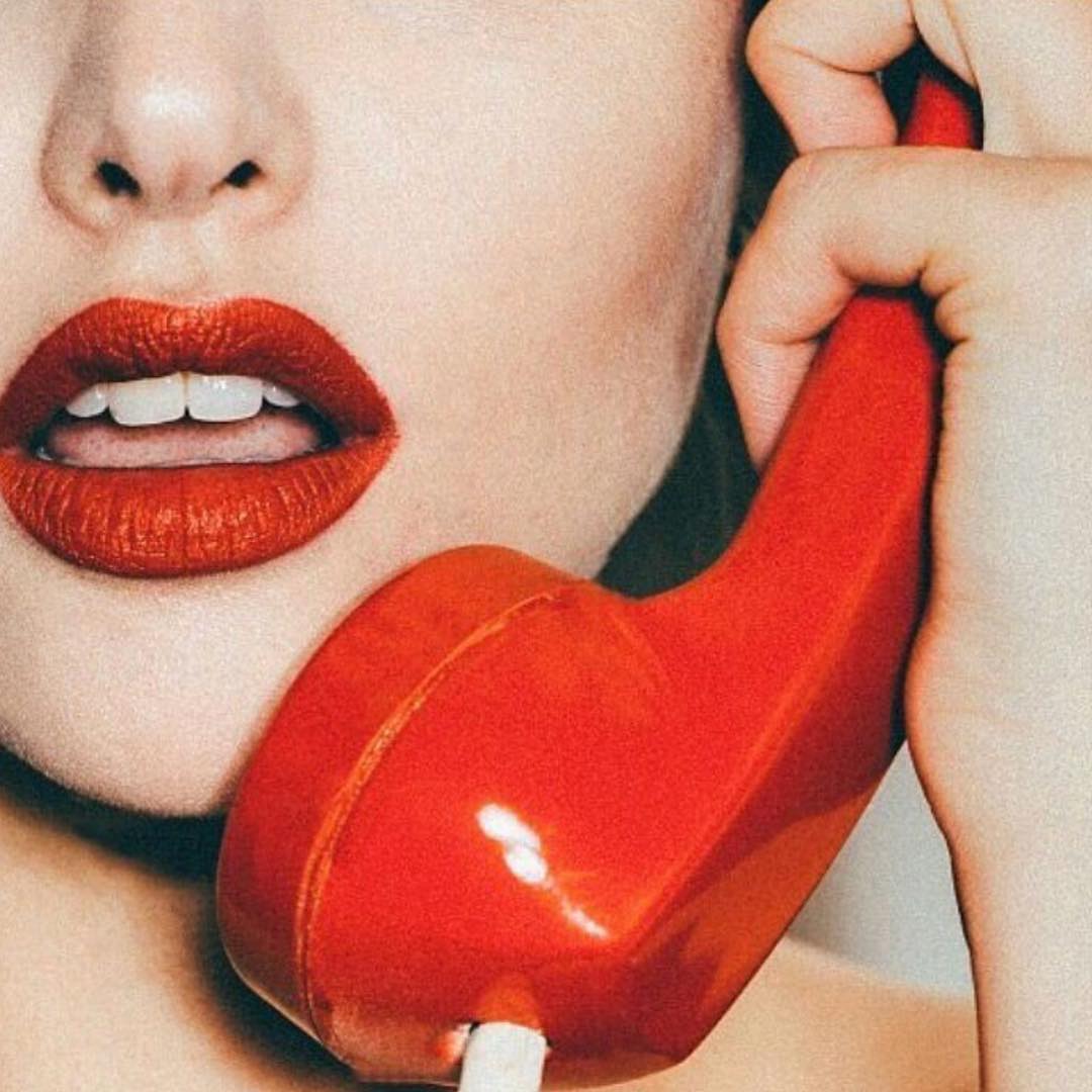 woman with red lipstick picking up the phone a woman wearing a red lipstick and with a red phone on her hand